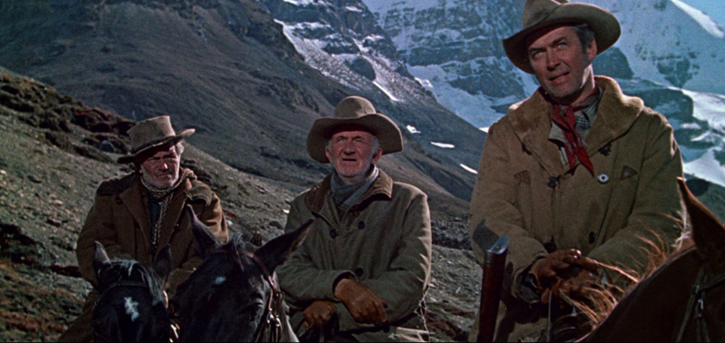 James Stewart, Walter Brennan, and Jay C. Flippen on horseback and wearing warm clothing against a backdro of majestic snow-covered mountains in The Far Country (1954)