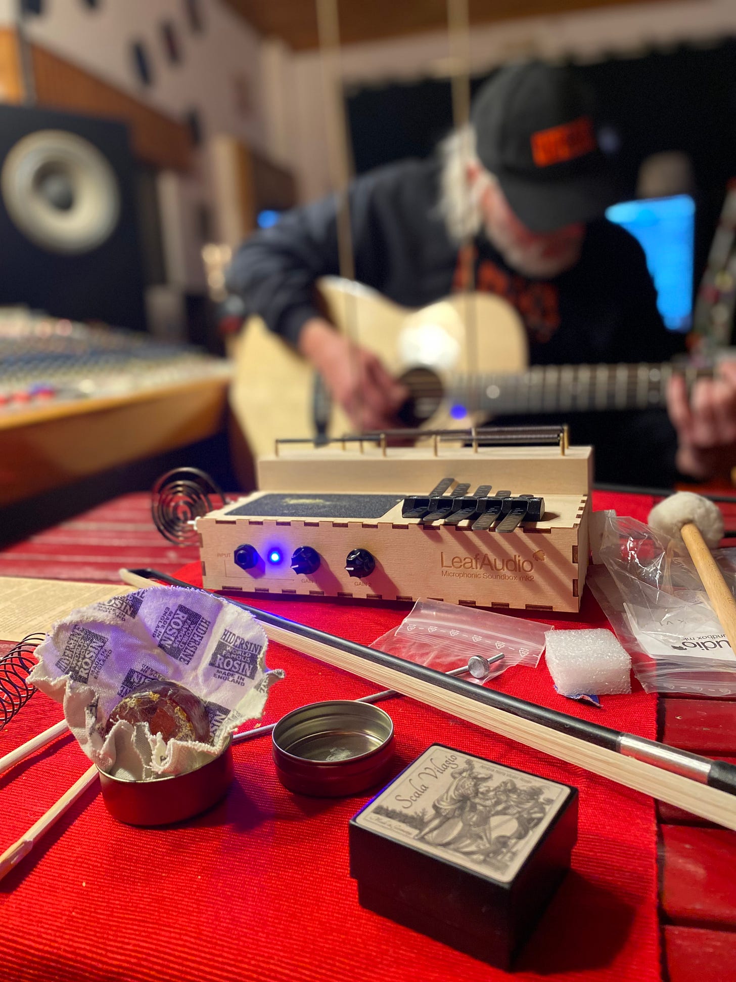 Leaf audio sound box, bow and resin on a table with Simon Campbell playing guitar in the Supertone studio, Samora Correia, Portugal