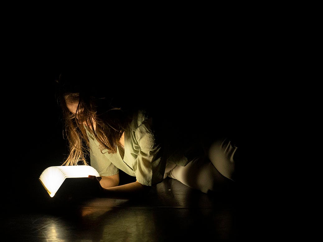 girl reading book in spotlight