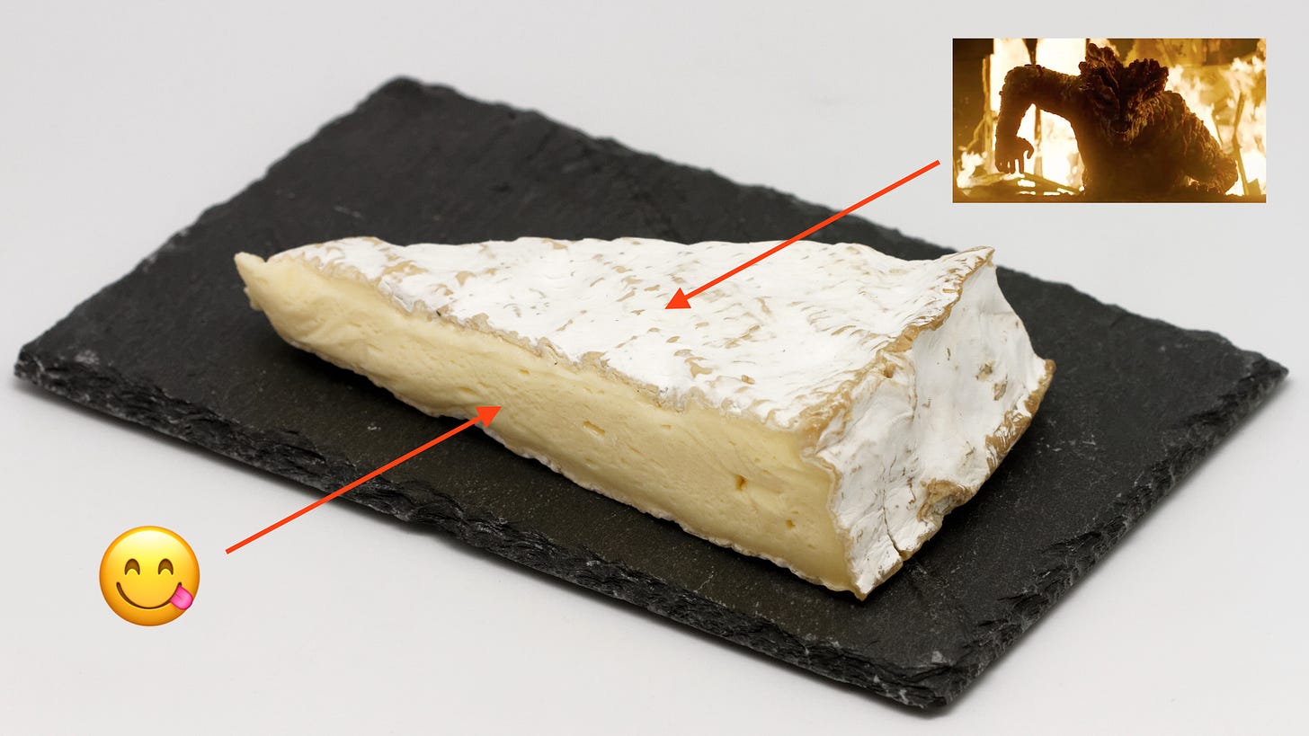 A wedge of brie on a slate black tile. An arrow points at the inside of the brie and has the "yum" emoji. Another arrow points at the rind and has the Bloater from The Last of Us
