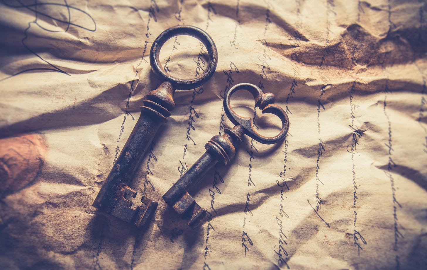 Two giant keys on crinkled yellow paper with cursive writing on it