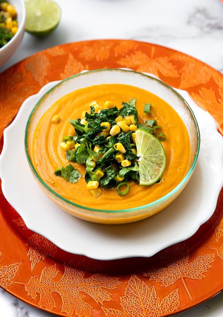 Creamy vegan sweet potato soup with corn and kale garnish