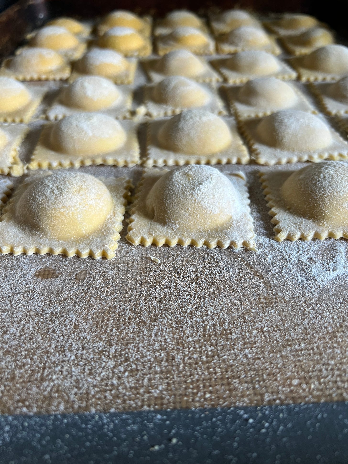 freshly shaped square ravioli lined up on a sheet pan