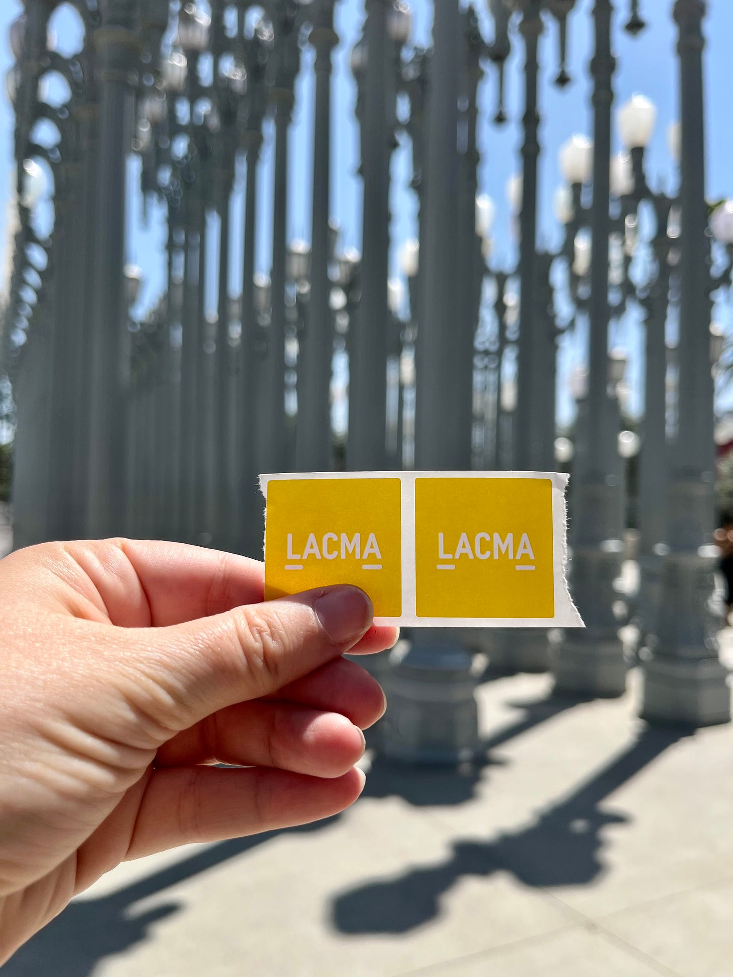 yellow LACMA entry sticker against Urban Light sculpture