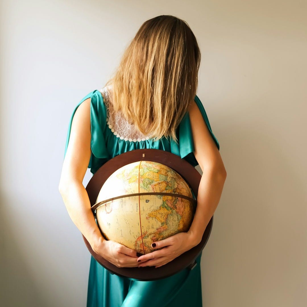 a woman in a green dress holding a globe