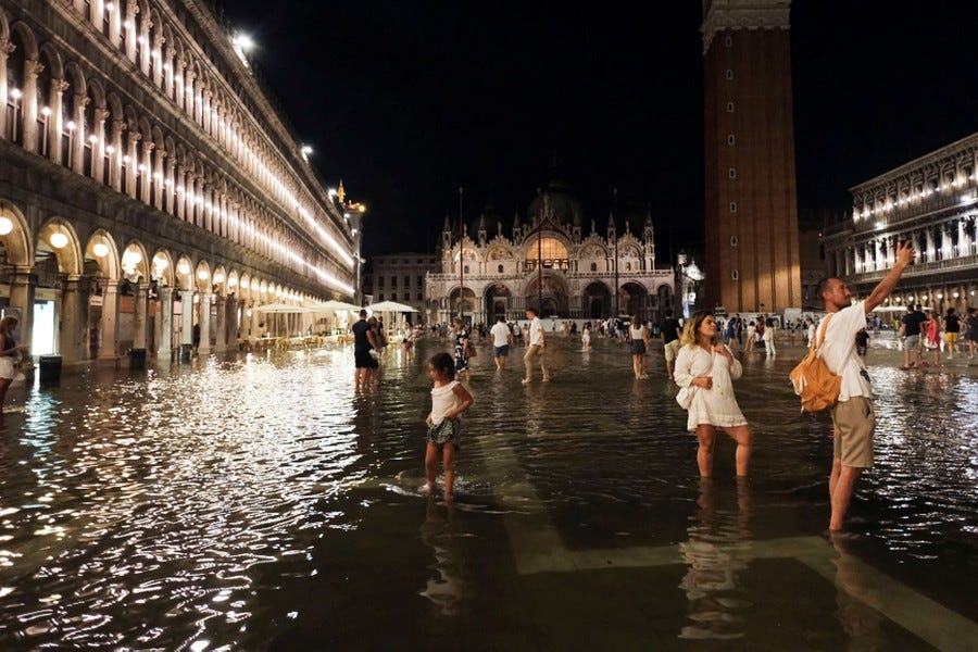Tourists walk through ankle-deep water in a flooded St Mark's Square in Venice.