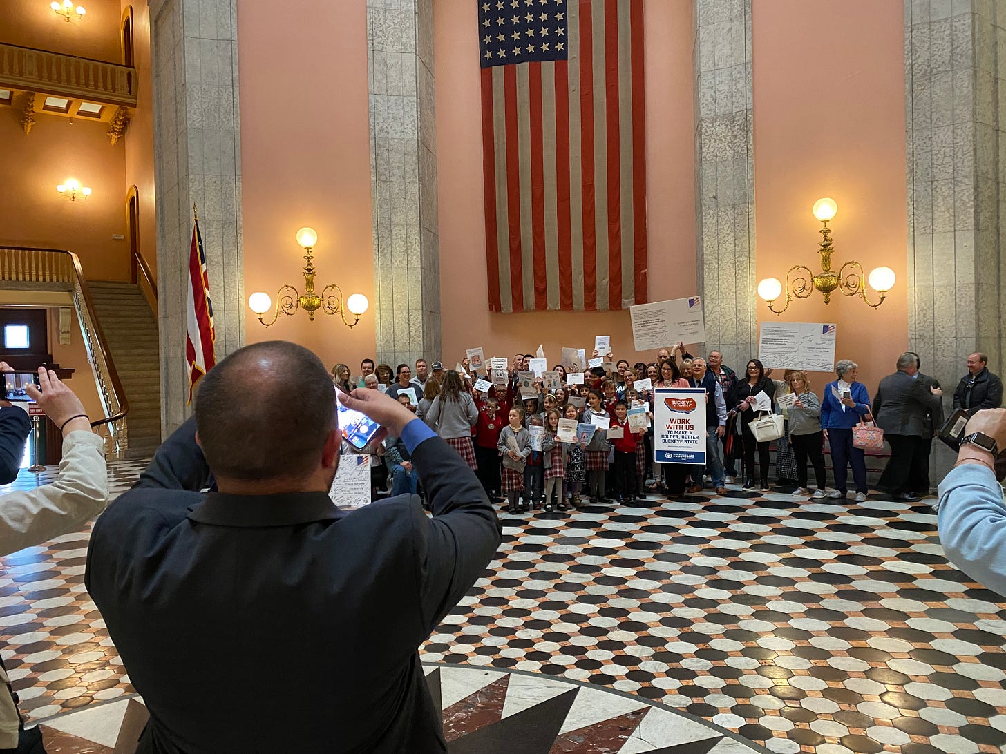 Donovan O’Neil, State Director of Americans for Prosperity, takes a picture of Backpack Bill supporters in the Statehouse Rotunda on Tuesday.