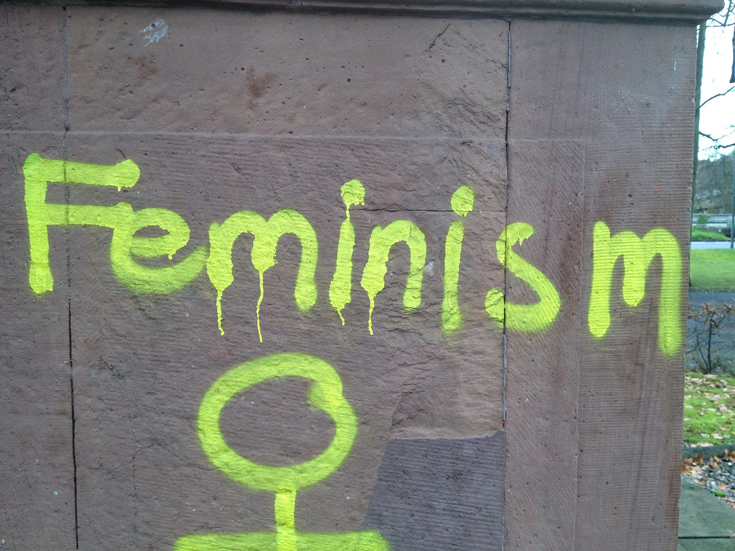 Feminism in gelbem Graffitti auf Sandstein gesprüht