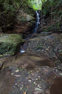 uma cachoeira com um pequeno balanço do lado