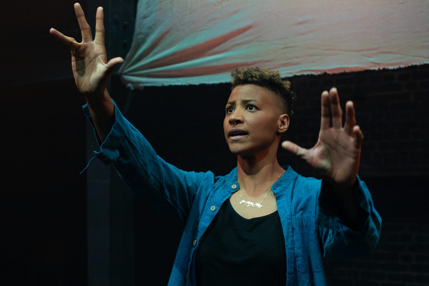 A photograph from Cutting the Tightrope showing an actor with their arms raised
