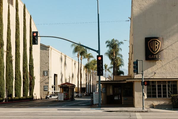 The exterior of the Warner Bros. studio with a red traffic light and palm trees.