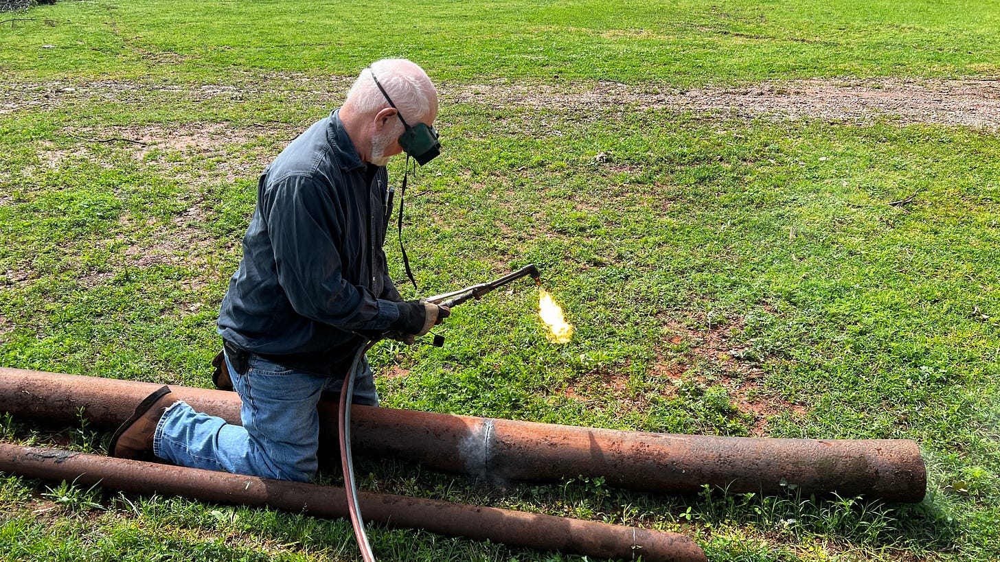 A man with a cutting torch cutting a large pipe