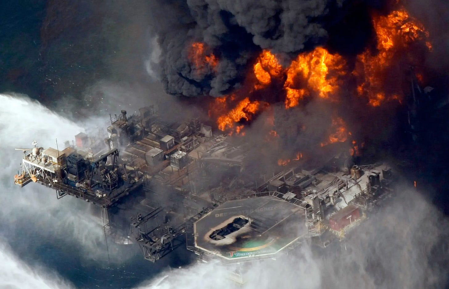 Aerial view of the Deep Water Horizon oil platform in the Gulf ablaze, billowing black smoke.