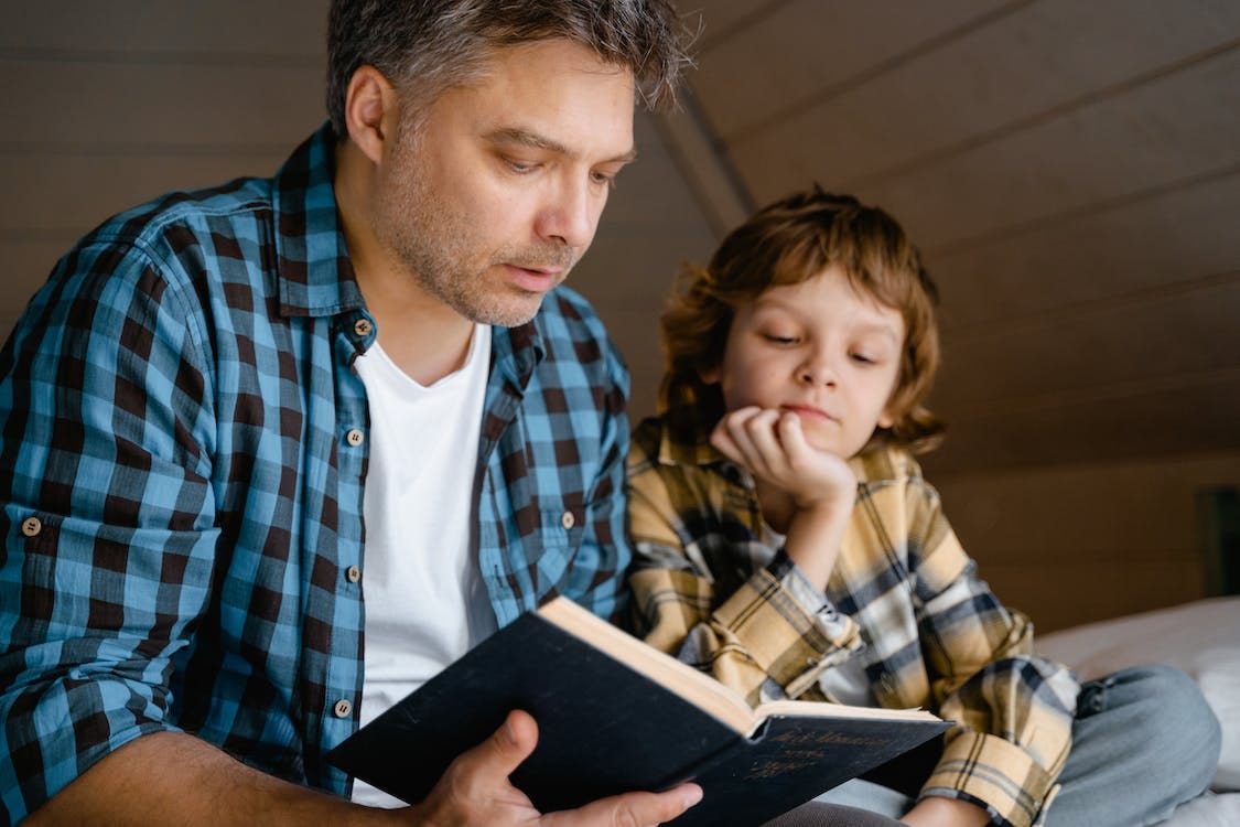 Free A Man Reading a Book to his Son Stock Photo