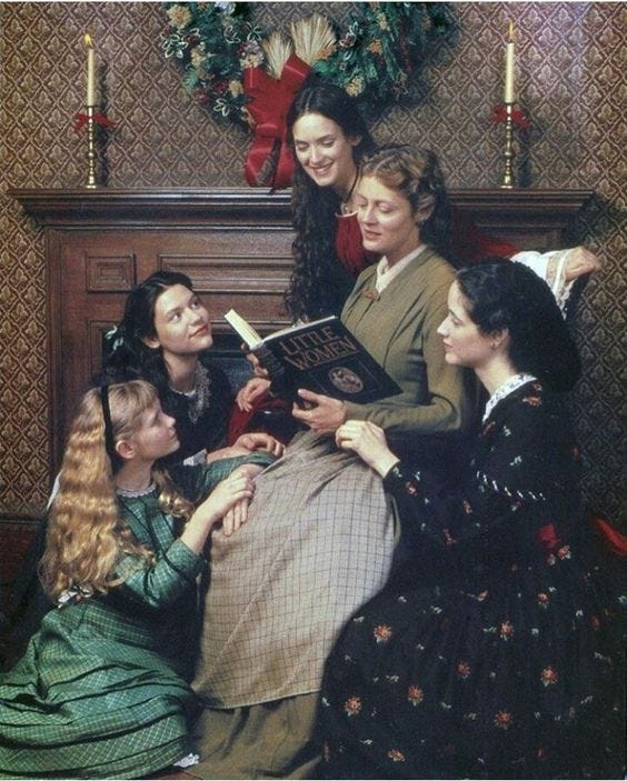 This may contain: a group of women sitting next to each other in front of a christmas wreath and fireplace