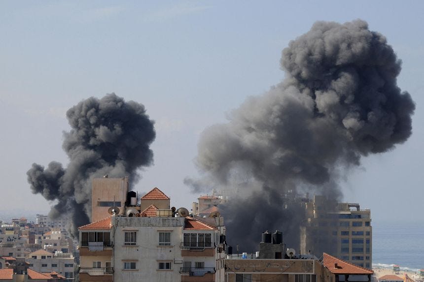 Smoke billows from residential buildings following Israeli air strikes in Gaza City on October 7.