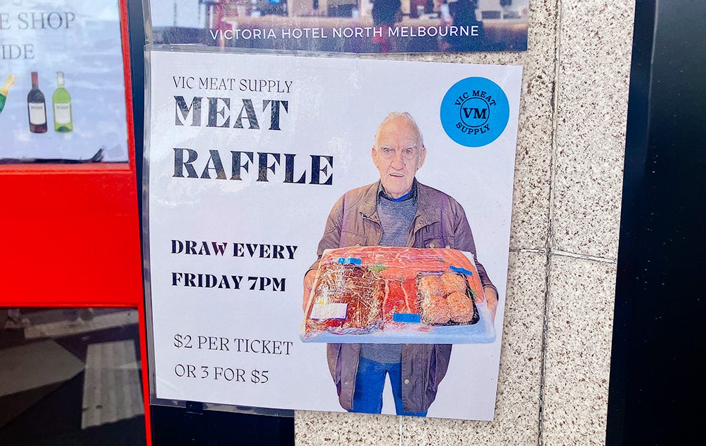 Dodgy poster on dodgy pub window for a meat raffle. on the dodgy poster is an old man sort of proudly holding a big meat tray. $2 a ticket or 3 for $5.