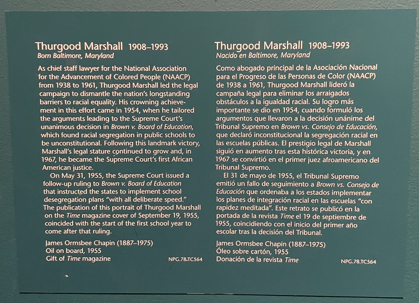 This is a photograph of the label for a portrait painting of Thurgood Marshall. It appears in English on the left, and Spanish on the right.   The English label reads:  “Thurgood Marshall 1908-1993 Born Baltimore, Maryland As chief staff lawyer for the National Association for the Advancement of Colored People (NAACP) from 1938 to 1961, Thurgood Marshall led the legal campaign to dismantle the nation’s longstanding barriers to racial equality. His crowning achievement in this effort came in 1954, when he tailored the arguments leading to the Supreme Court’s unanimous decision in Brown v. Board of Education, which found racial segregation in public schools to be unconstitutional. Following this landmark victory, Marshall’s legal stature continued to grow and, in 1967, he became the Supreme Court’s first African American justice. On May 31, 1955, the Supreme Court issued a follow-up ruling to Brown v. Board of Education that instructed the states to implement school desegregation plans ‘with all deliberate speed.’ The publication of this portrait of Thurgood Marshall on the Time magazine cover of September 19, 1955, coincided with the start of the first school year to come after that ruling. James Ormsbee Chapin (1887-1975) Oil on board, 1955 Gift of Time magazine NPG.78.TC564”  The Spanish label reads: “Thurgood Marshall 1908-1993 Nacido en Baltimore, Maryland Como abogado principal de la Asociación Nacional para el Progreso de las Personas de Color (NAACP) de 1938 a 1961, Thurgood Marshall lideró la campana legal para eliminar los arraigados obstáculos a la igualdad racial. Su logro más importante se dio en 1954, cuando formuló los argumentos que llevaron a la decision unánime del Tribunal Supremo en Brown vs. Consejo de Educación, que declare inconstitucional la segregación racial en las escuelas públicas. El prestigio legal de Marshall siguió en aumento tras esta histórica Victoria, y en 1967 se convirtió en el primer juez afroamericano del Tribunal Supremo. El 31 de mayo de 1955, el Tribunal Supremo emitió un fallo de seguimiento a Brown vs. Consejo de Educación que ordenaba a los estados implementar los planes de integración racial en las escuelas “con rapidez meditada”. Este retrato se publicó en la portada de revista Time el 19 de septiembre de 1955, coincidiendo con el inicio del primer año escolar tras la decision del Tribunal. James Ormsbee Chapin (1887-1975) Óleo sobre carton, 1955 Donación de la revista Time NPG.78.TC564”