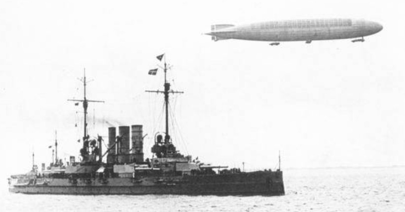 A black and white photo showing Zeppelin L.31 flying a few hundred feet above the warship SMS Ostfriesland.