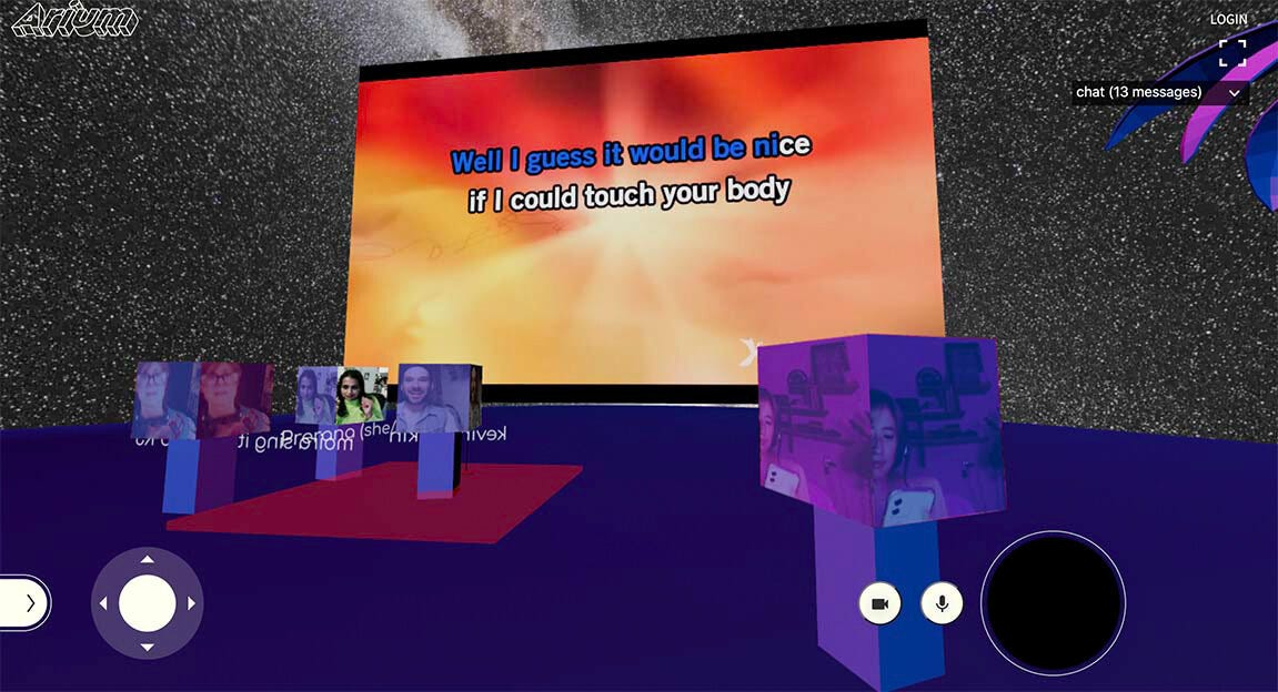 A screenshot of a 3D virtual space with a large video plane mid-karaoke with the words “Well I guess it would be nice if I could touch your body” on a red and orange background. There are various audience members with avatars that have block heads.