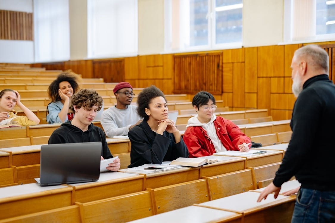 Free Students from diverse backgrounds engaged in a university lecture setting. Stock Photo Free Students from diverse backgrounds engaged in a university lecture setting. Stock Photo