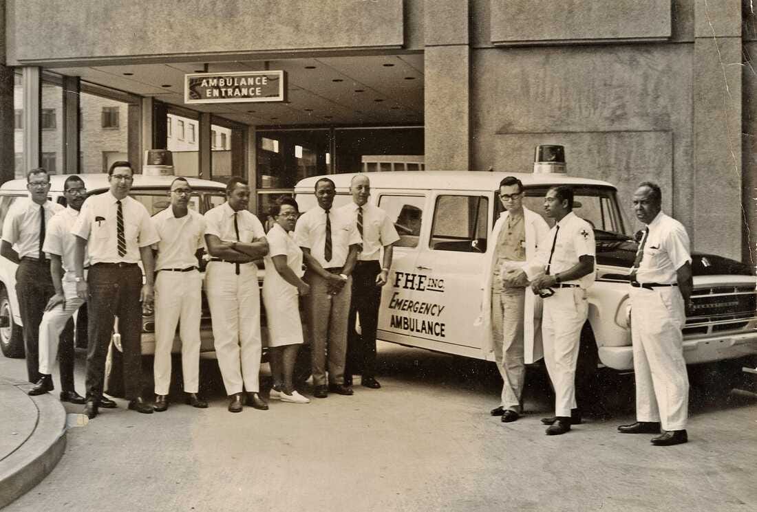 paramedics from the 1960s standing next to an ambulance