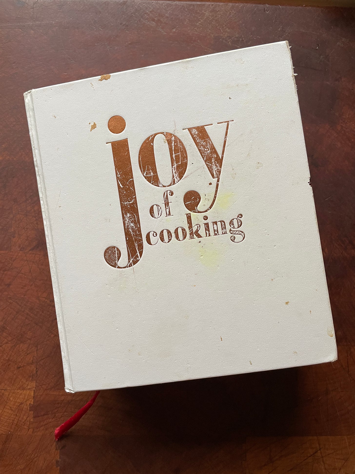 A copy of the Joy of Cooking cookbook with a stained and scratched cover