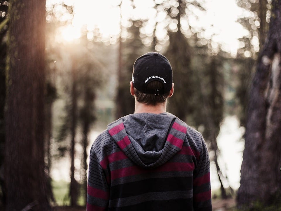 selective focus photo of man standing front of trees at daytime