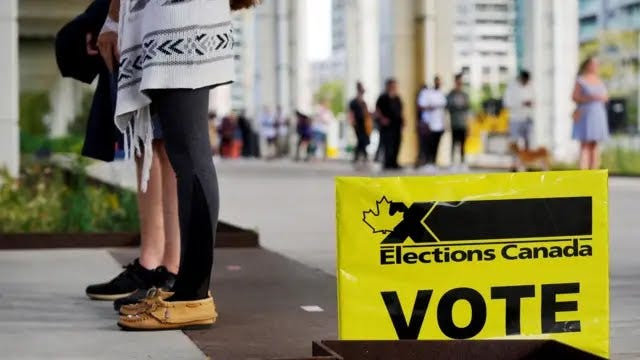 Two pairs of feet alongside a sign that says "Vote" and "Elections Canada"