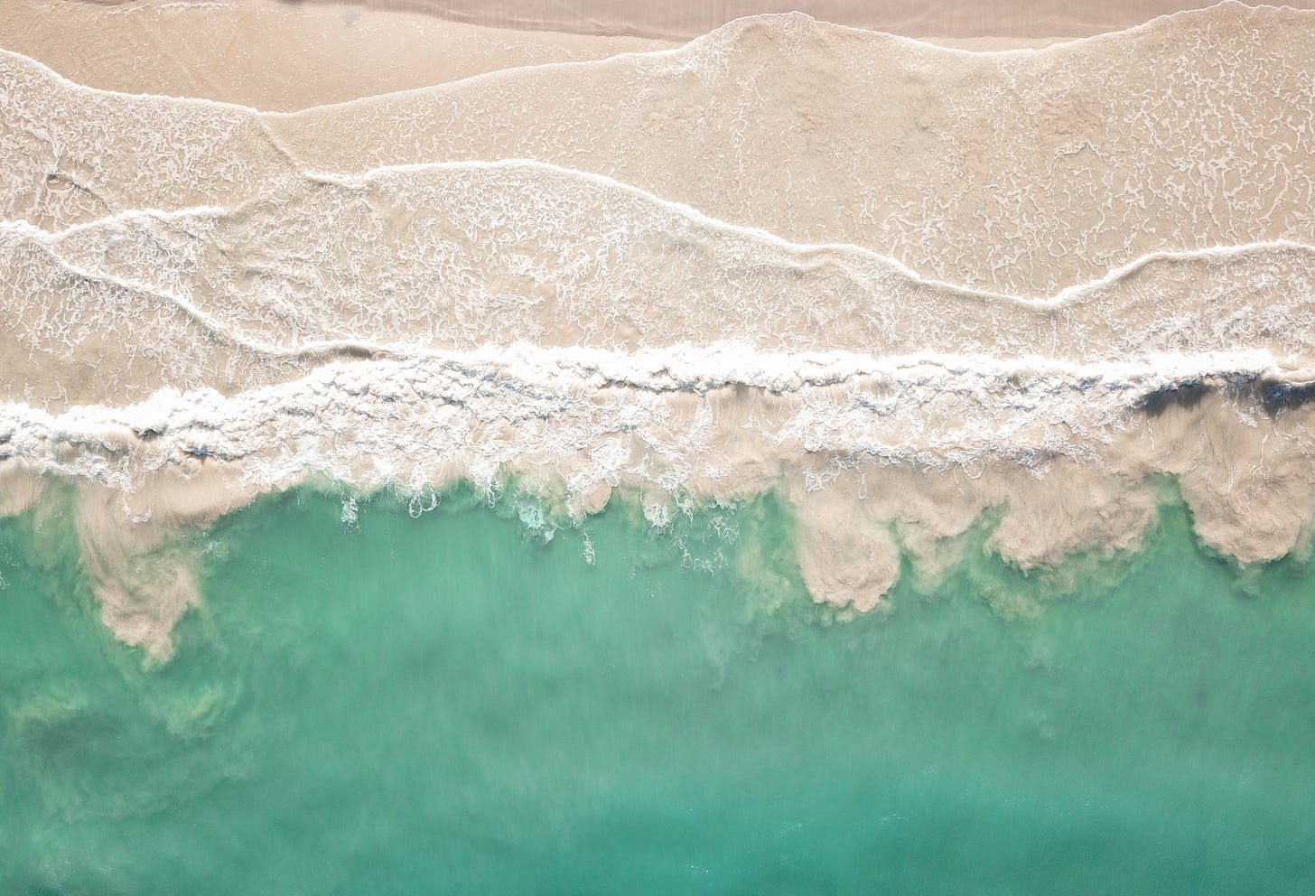 A very beautiful overhead shot of waves lapping at a beach