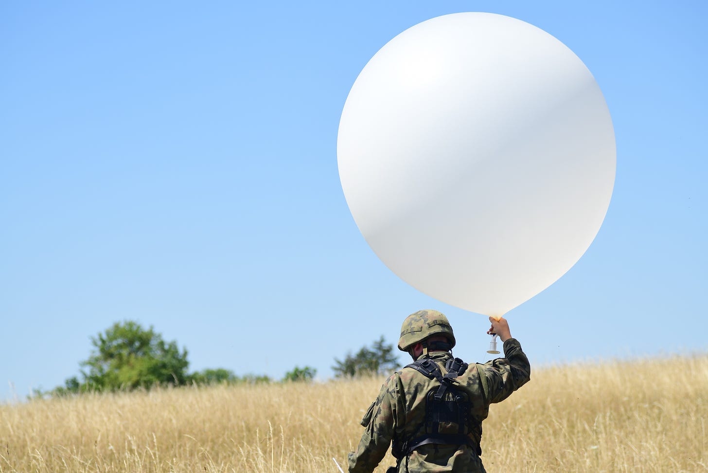 Polish soldiers assigned to 2nd Battalion, 5th Artillery Brigade, prepare to launch a meteorological balloon prior to the unit conducting a fire mission with their AHS Krab self-propelled howitzers as part of exercise Dynamic Front 22 (DF 22) at the 7th Army Training Command's Grafenwoehr Training Area, Germany, July 18, 2022. DF22, led by 56th Artillery Command and U.S. Army Europe and Africa directed, is the premier U.S. led NATO Allied and Partner integrated fires exercise in the European Theater focusing on fires interoperability and increasing readiness, lethality and interoperability across the human, procedural, and technical domains.(U.S. Army photo by Kevin Sterling Payne) 