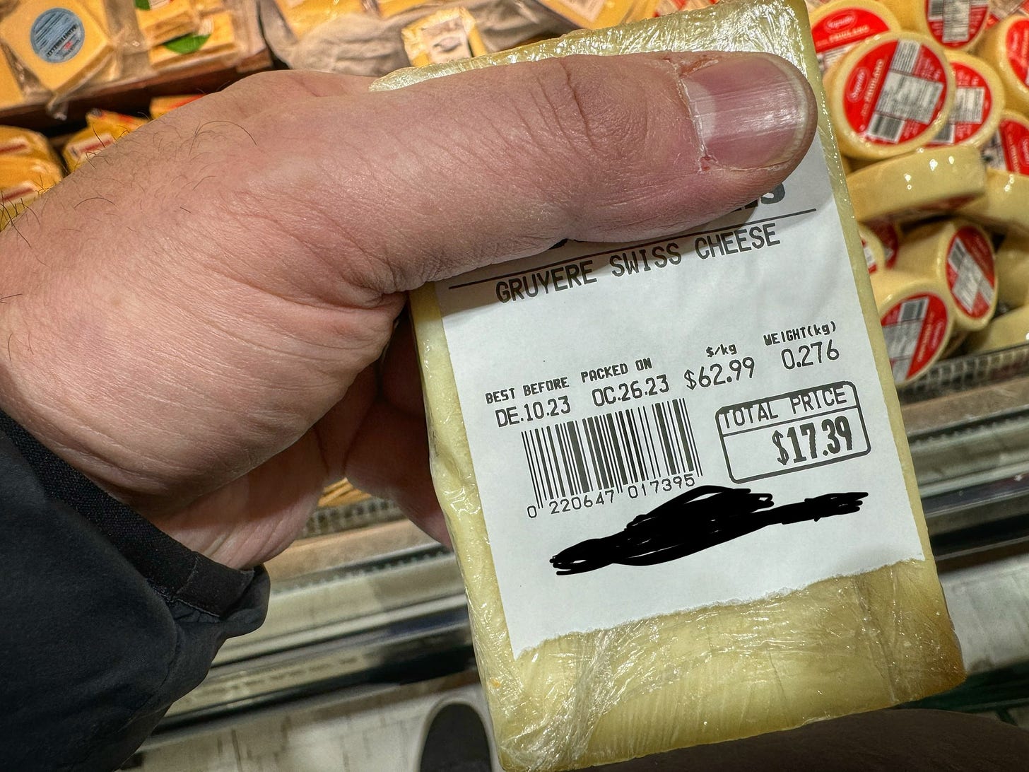A piece of Gryuere cheese at a supermarket. 0.276 kg costs $17.39. The price per kilogram is $62.99