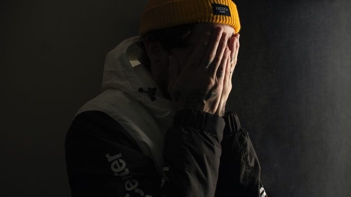 A person in a yellow beanie covering his face

Description automatically generated