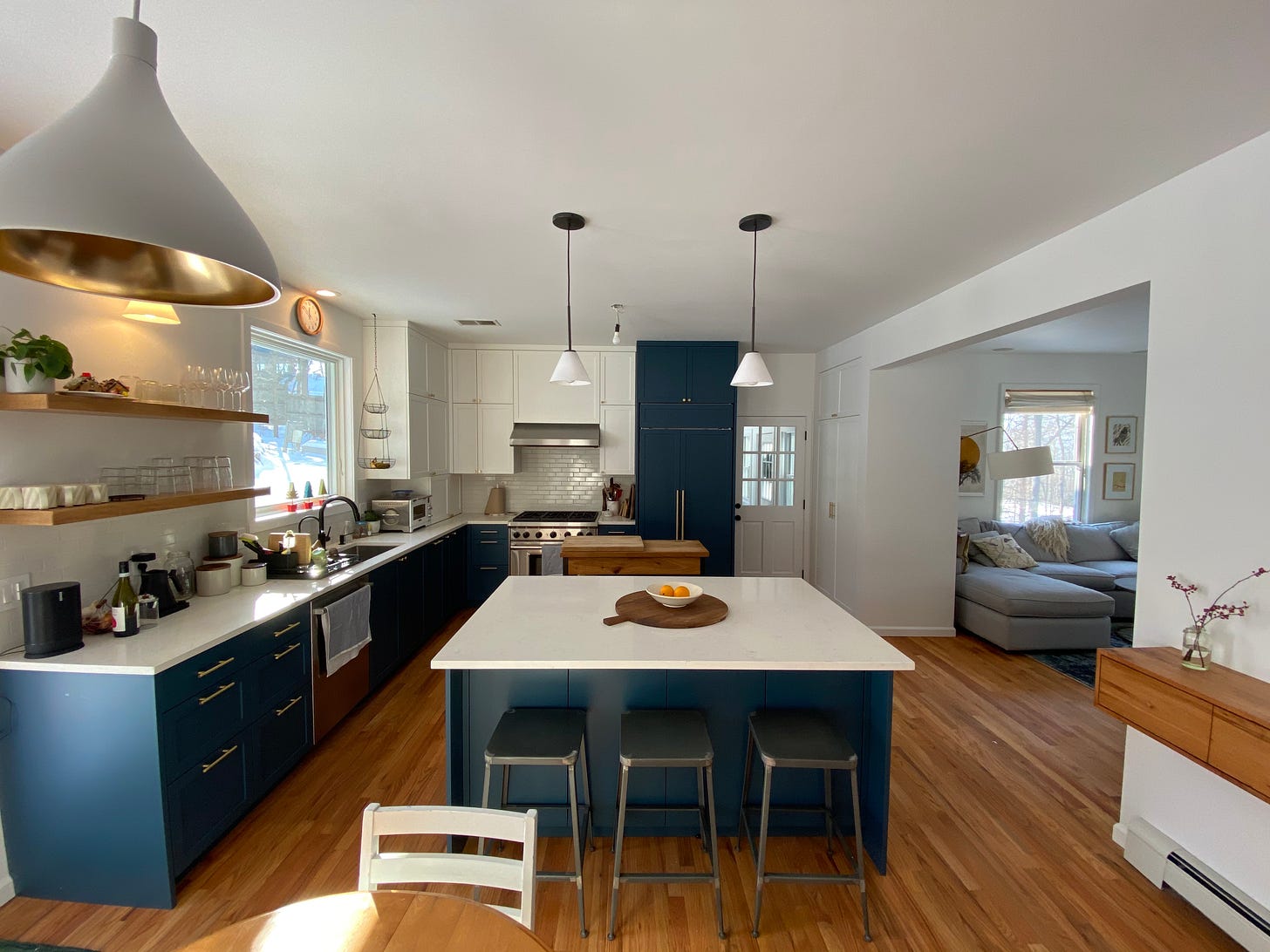 Kitchen with white and blue cupboards and a island in the centre with a white top and blue base.