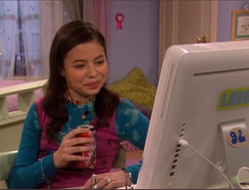 a young Miranda Cosgrove as her character Megan on Drake & Josh, sitting at her computer and smirking
