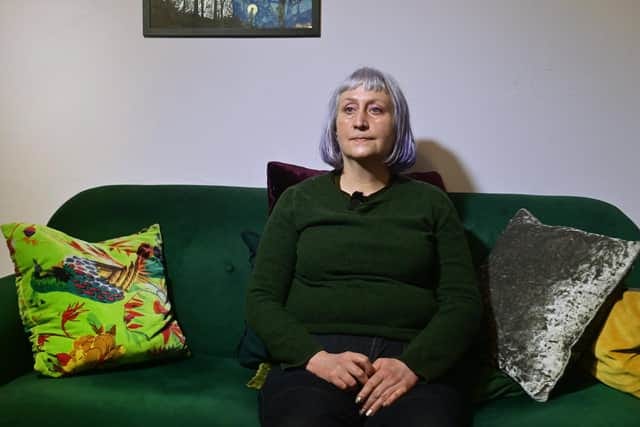 A white femme with a white-purple ombre bob haircut is sitting on a green couch, looking pissed off.