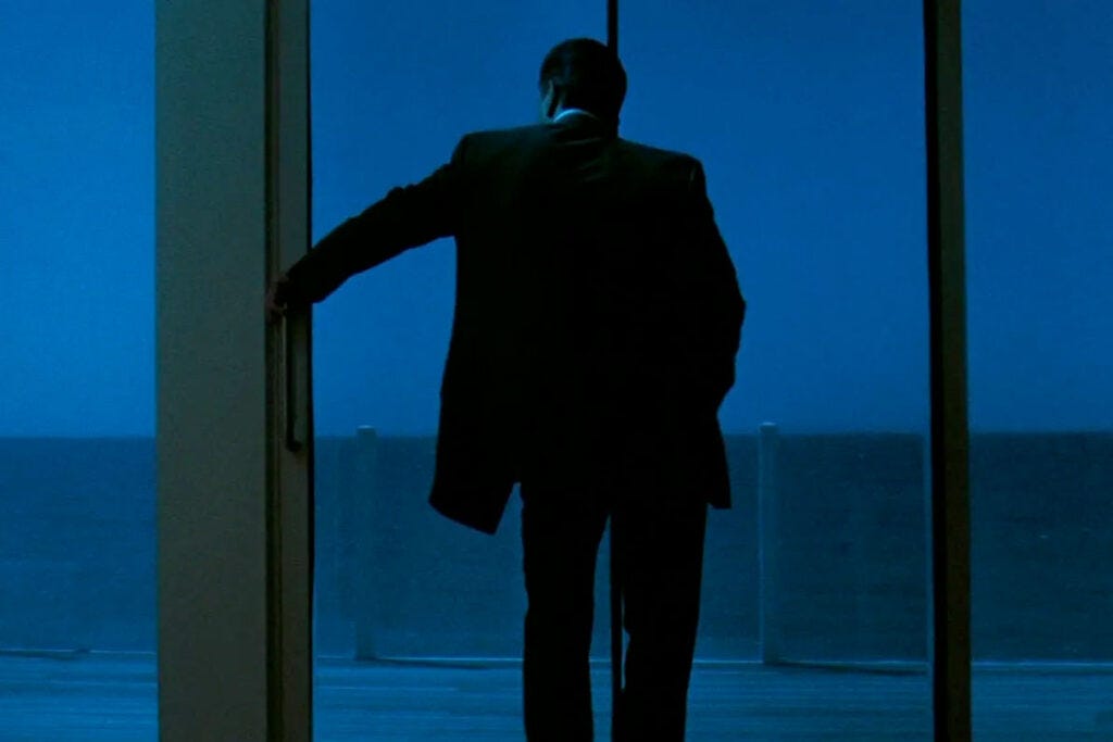 Robert De Niro, in silhouette, looks out of over the ocean from his modernist apartment in Michael Mann's film Heat