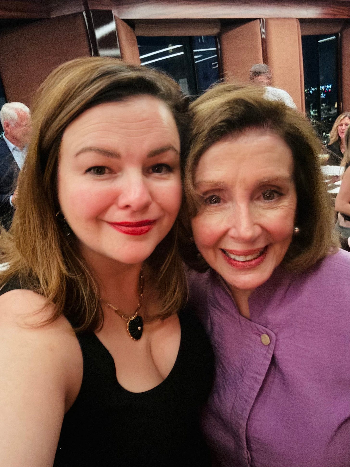 Speaker Emerita Nancy Pelosi and Amber Tamblyn take a selfie together. Their arms are around each other and their heads touch as they both look into the camera and smile.