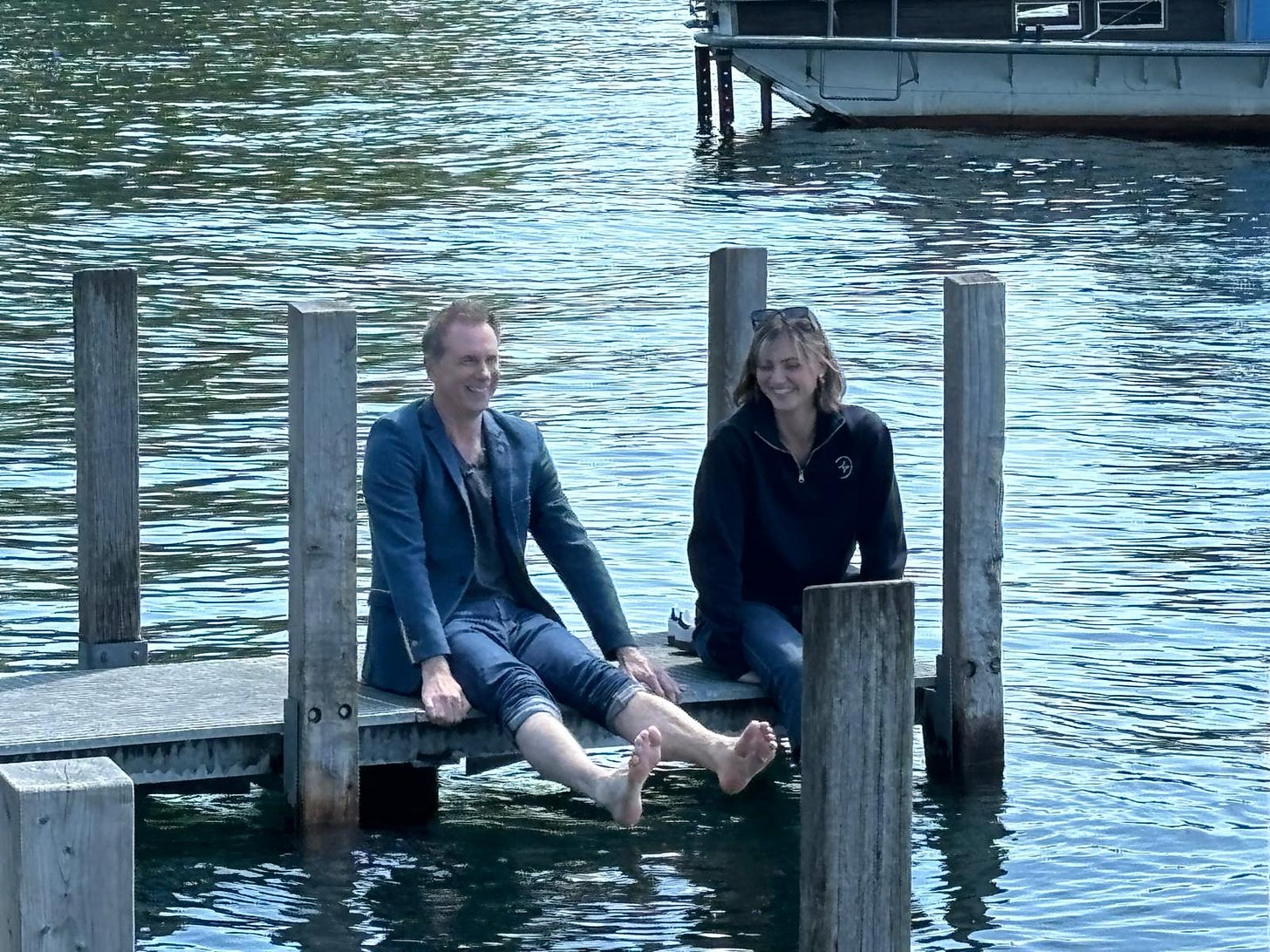 Spencer and guest sitting on a pontoon. Spen's feet are lifted out of the water