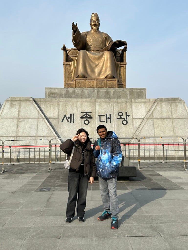 A person and person standing in front of a statue

Description automatically generated