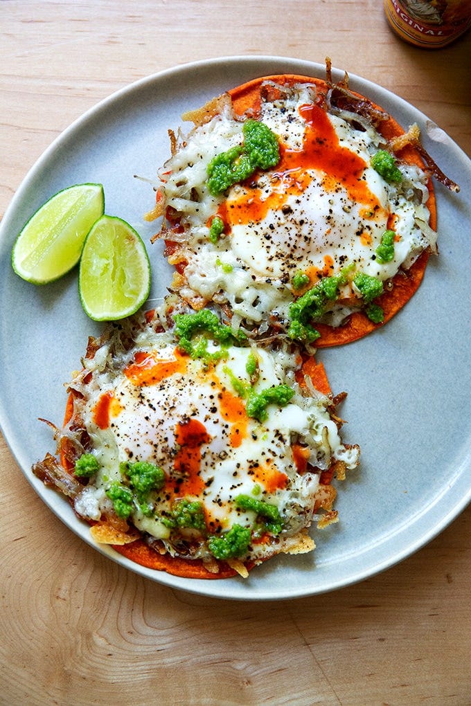 A plate of crispy potatoes, egg, and cheese on tortillas.