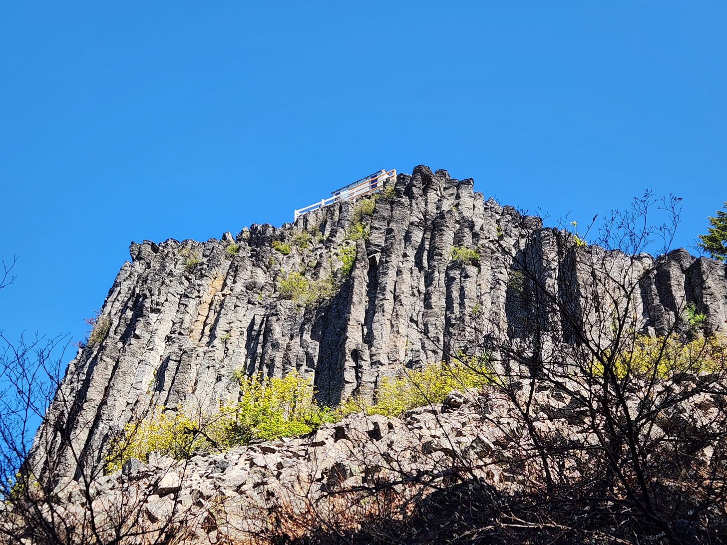 looking up at basalt columns with the edge of a white fire lookout visible