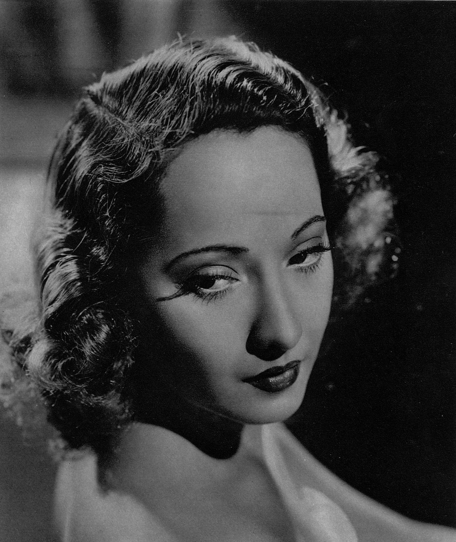 black and white closeup portrait of Merle Oberon looking down