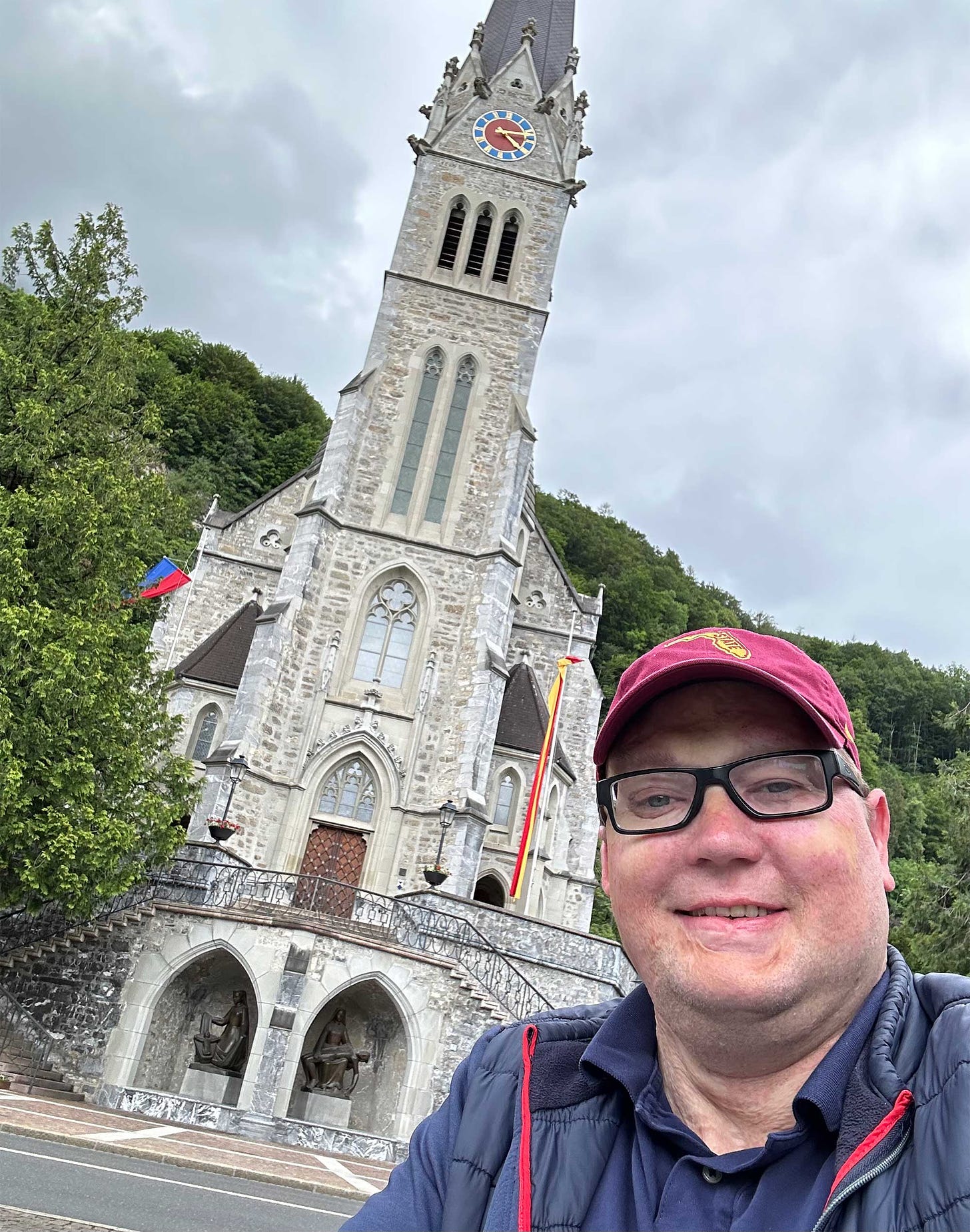 Selfie of John in front of cathedral with trees surrounding it.