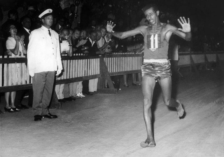 Abebe Bikila ao cruzar, descalço, a linha de chegada da maratona dos Jogos de Roma, em 1968