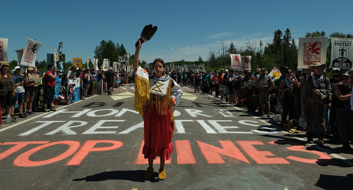 A young Native American protestor stands amidst a protest against Line 3 