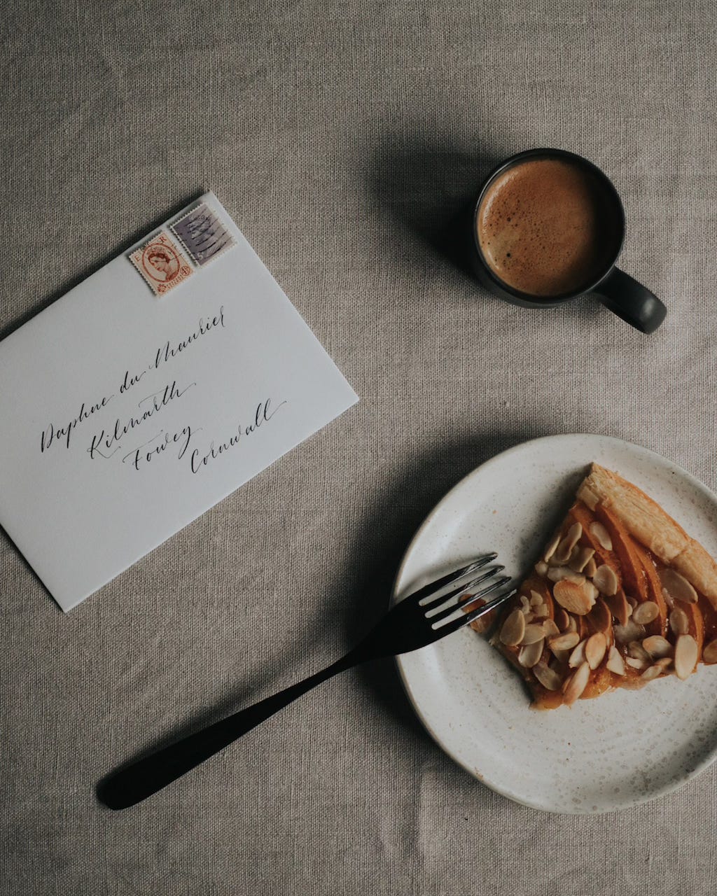 Envelope addressed to Daphné du Maurier, coffee cup and fruit tart on a table