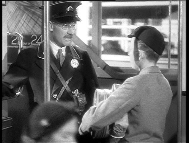 Stevie played by Desmond Tester, unsuspectingly boards a bus with a bomb and speaks to the conductor, in Alfred Hitchcock’s 1936 film Sabotage