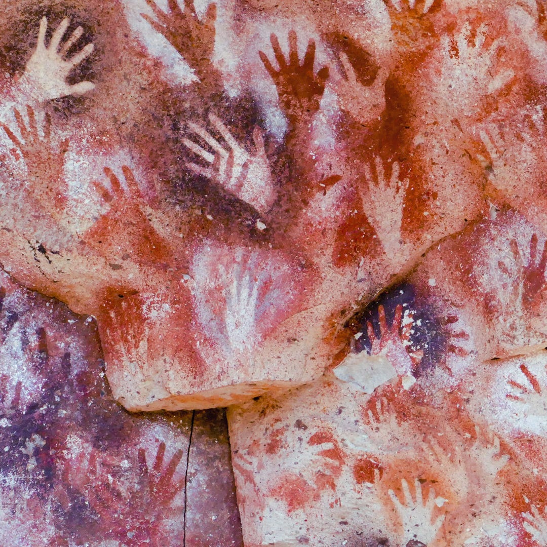 Red stenciled handprints on an ancient cave wall in Argentia