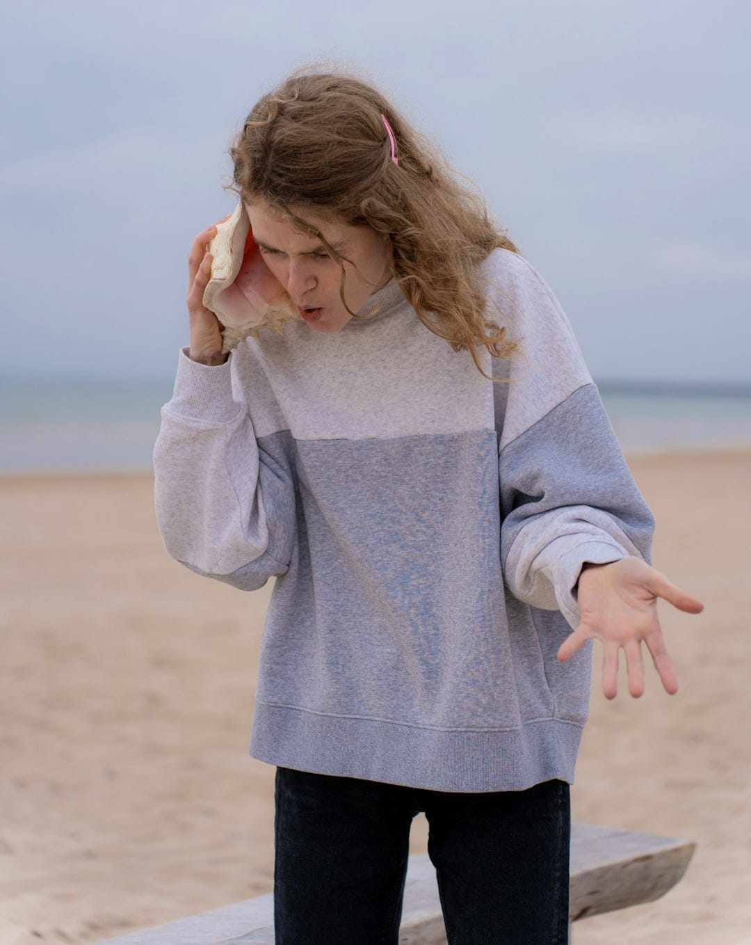 a woman standing on a beach holding a hot dog a woman standing on a beach holding a hot dog